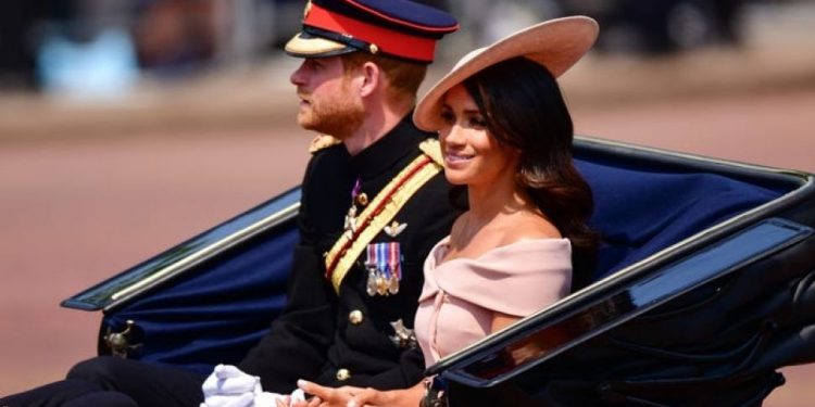 Gaya busana Meghan Merkle mengenakan gaun off shoulder.